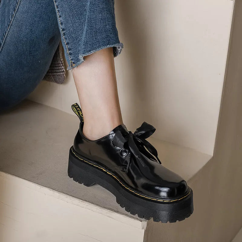Women's white lace-up leather shoes with thick soles and black cross straps on the ankle.