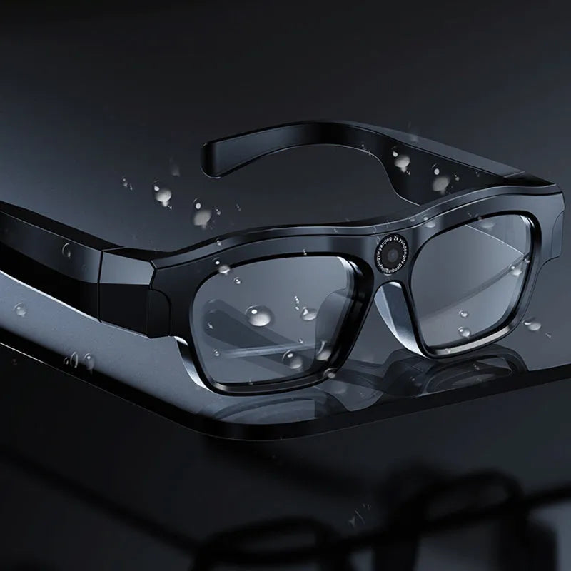 Black head-mounted smart Bluetooth glasses with a transparent lens on a colour box.