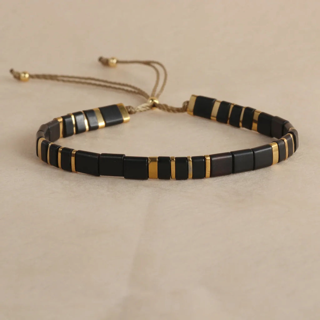 Geometric glass and coloured glaze beaded bracelet in milky white, black, green, blue, or red.