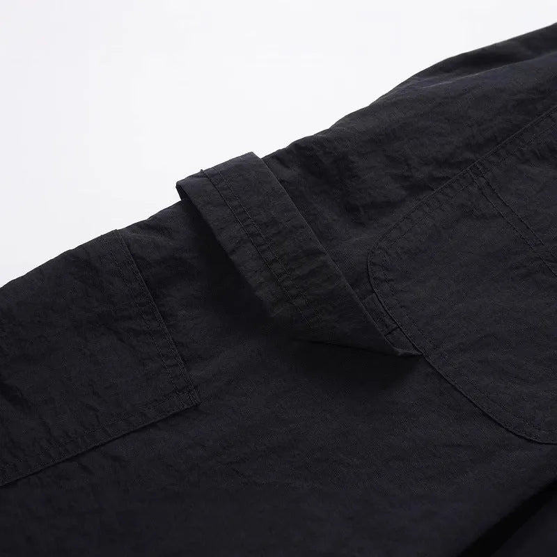 Men's baggy paratrooper pants in black with elastic waist and drawstring, side view on model