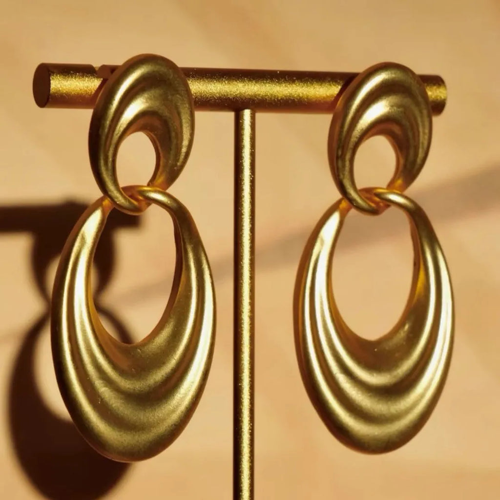 A pair of gold-toned double circle earrings with a textured quicksand finish on a copper base.