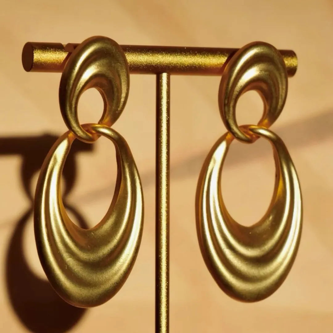 A pair of gold-toned double circle earrings with a textured quicksand finish on a copper base.