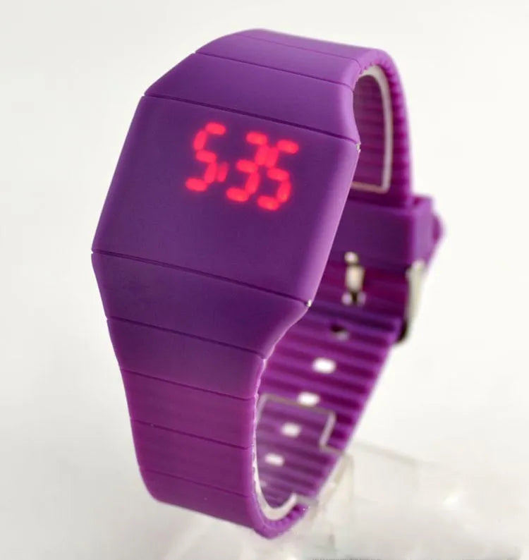 Square plastic electronic watch with digital display on a coloured PU strap, showing touch screen and button controls.