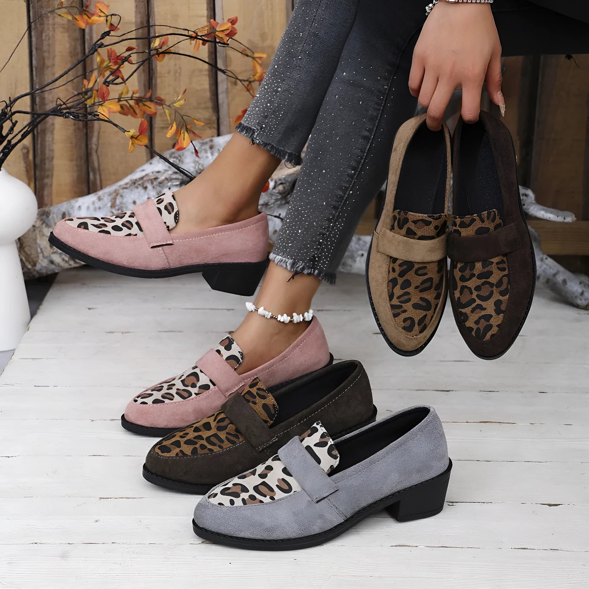 Women's leopard print suede slip-on shoe with a chunky mid heel and pointed toe on a brown background.