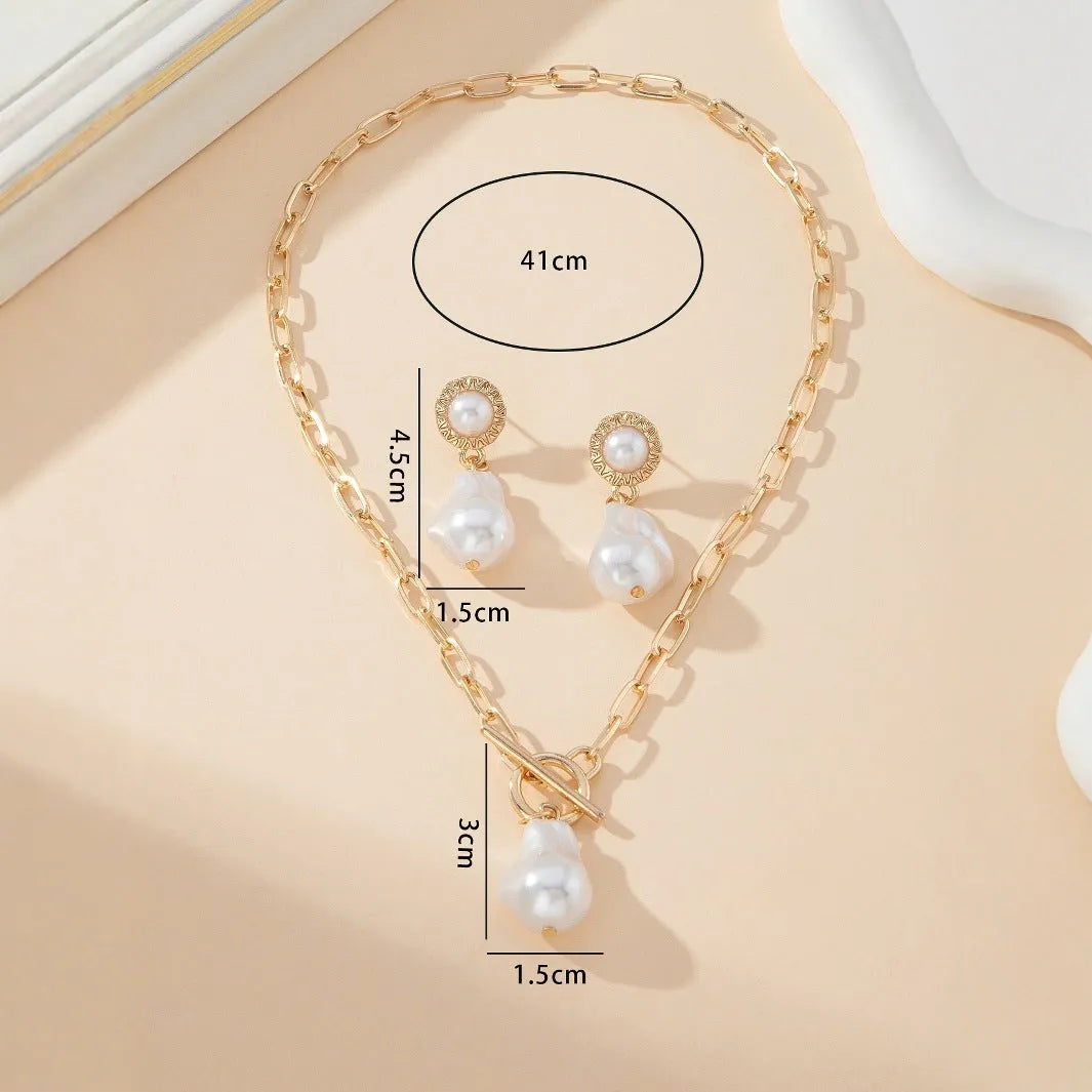 Gold tone baroque pearl pendant necklace and matching ear stud set on display