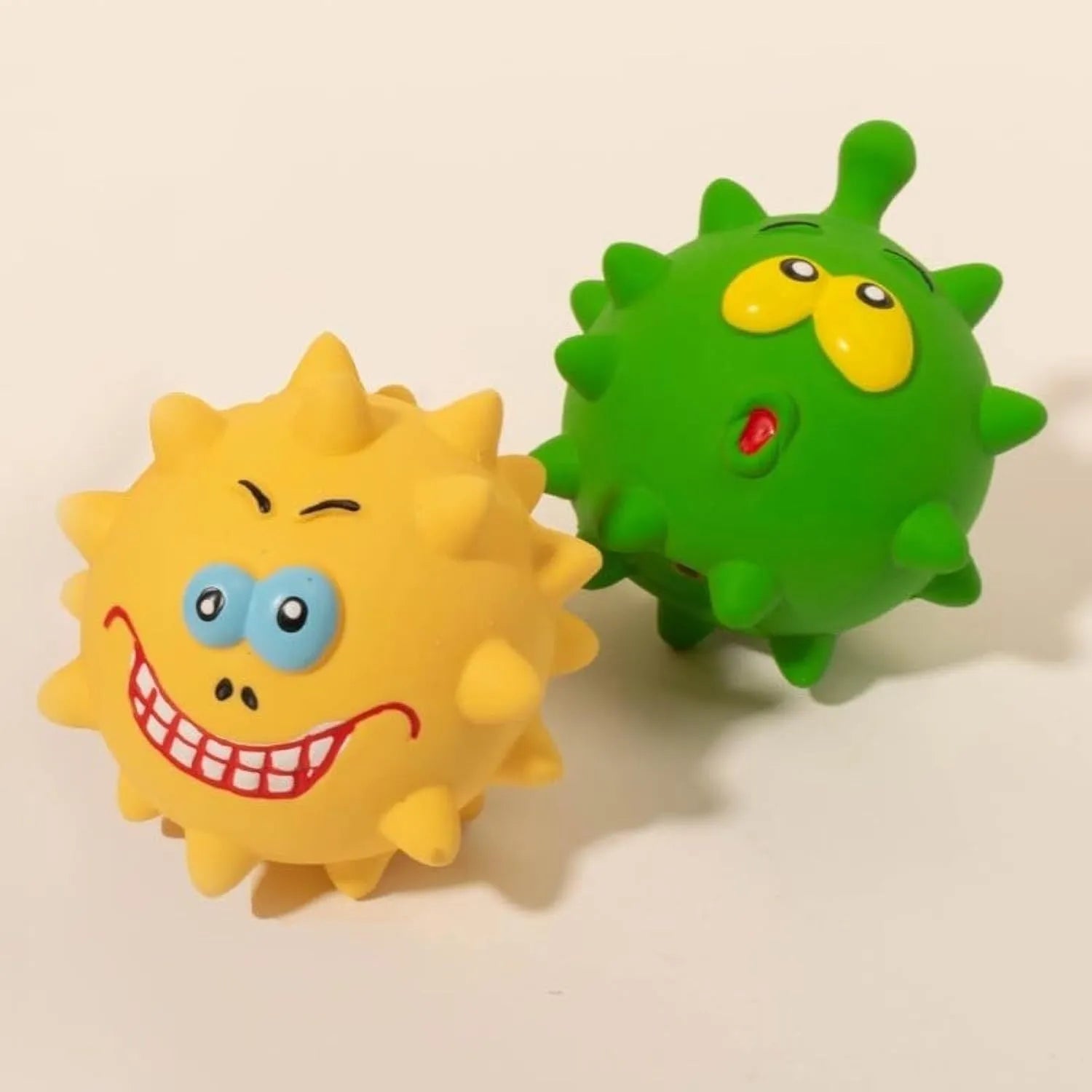 Set of four colourful natural latex squeaky dog balls with cute faces on a blue, green, red, and yellow background