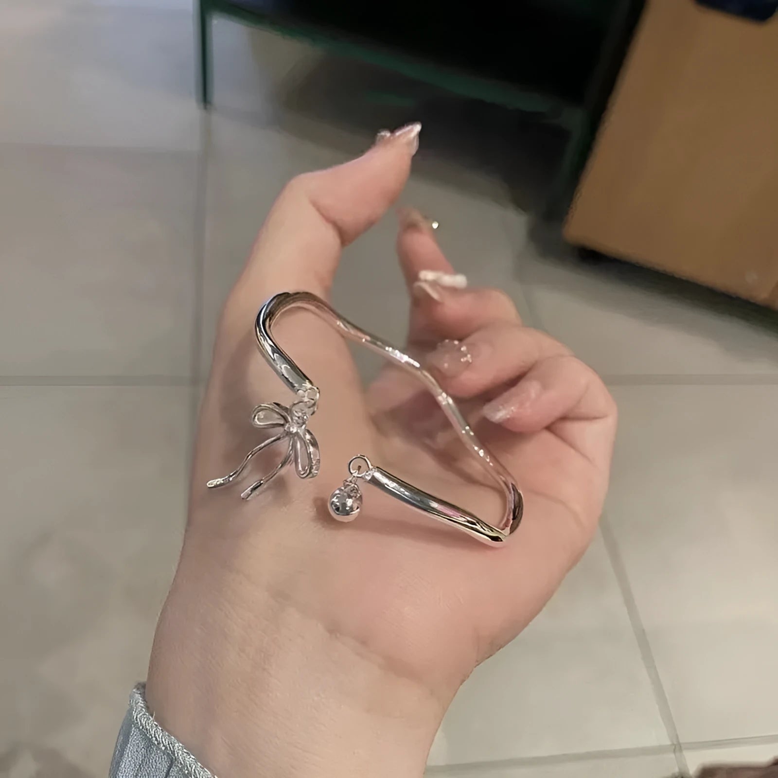 Adjustable silver bracelet with bow design and opening clasp on zinc alloy base