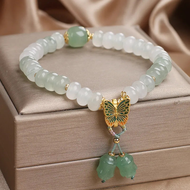 Tian Shan Cui green crystal abacus beads bracelet with butterfly tassel, pearls, and rhinestones on white background