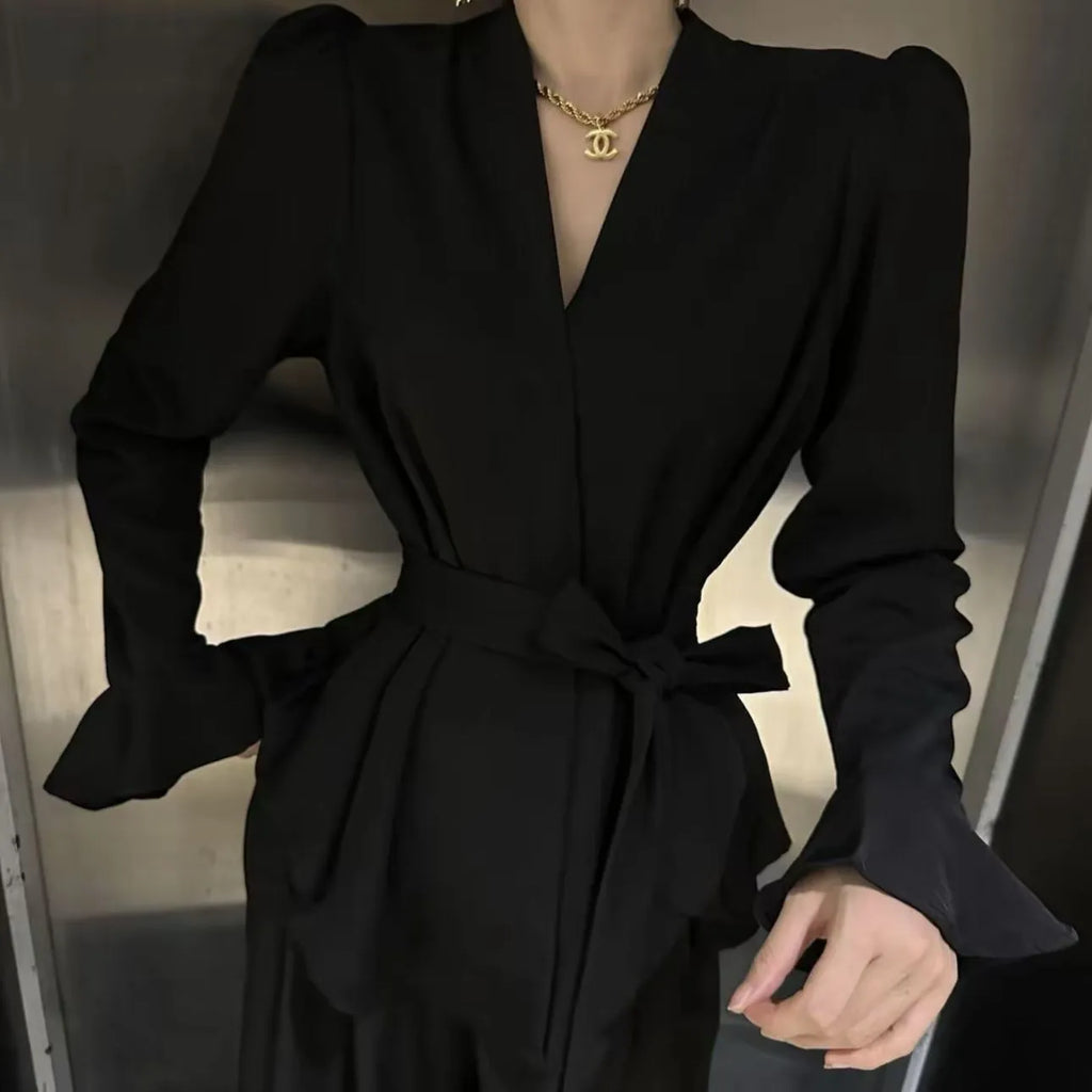 Women's black French-style shirt with an irregular collar and long bell sleeves, showing the tied front closure.