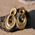 A pair of gold-toned double circle earrings with a textured quicksand finish on a copper base.