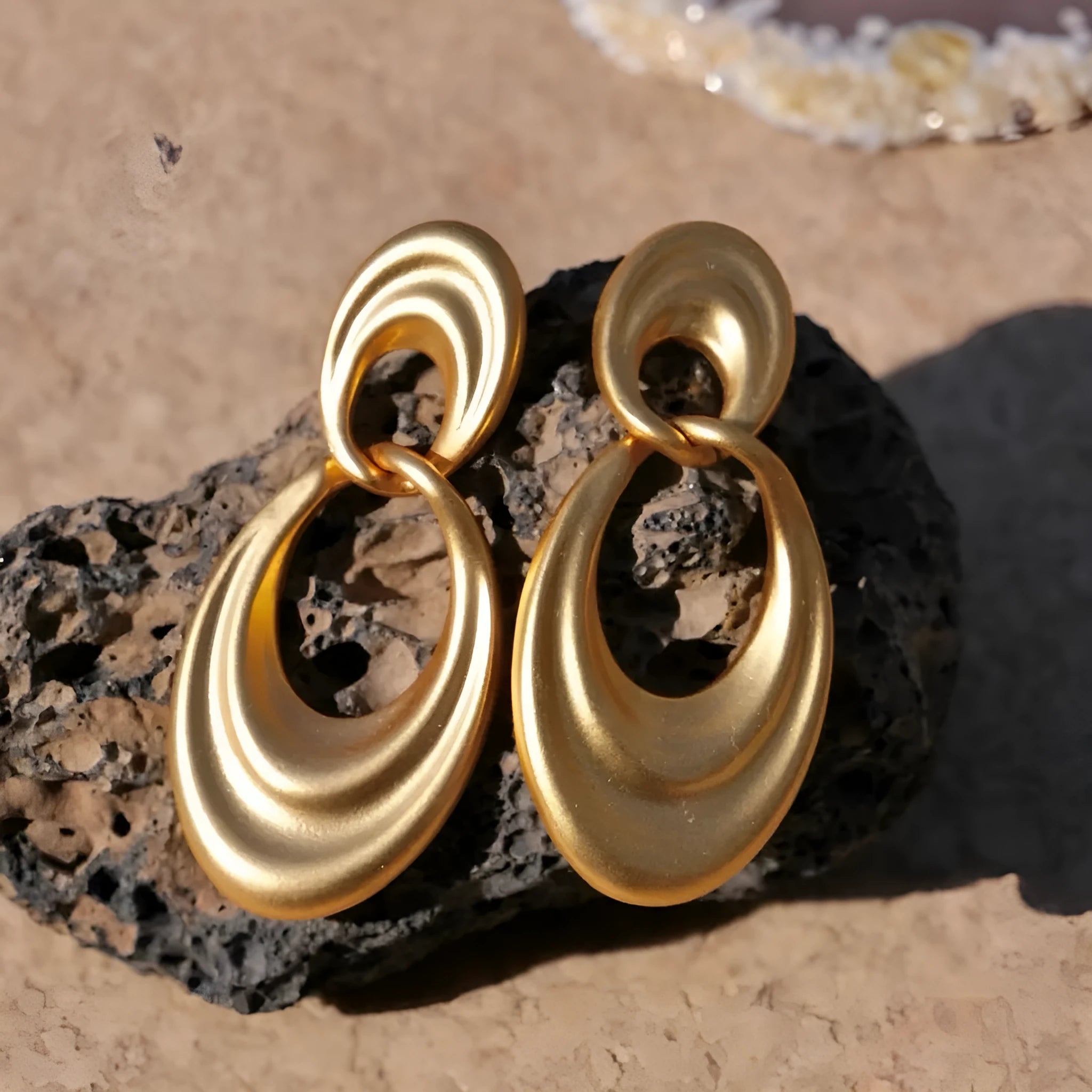 A pair of gold-toned double circle earrings with a textured quicksand finish on a copper base.
