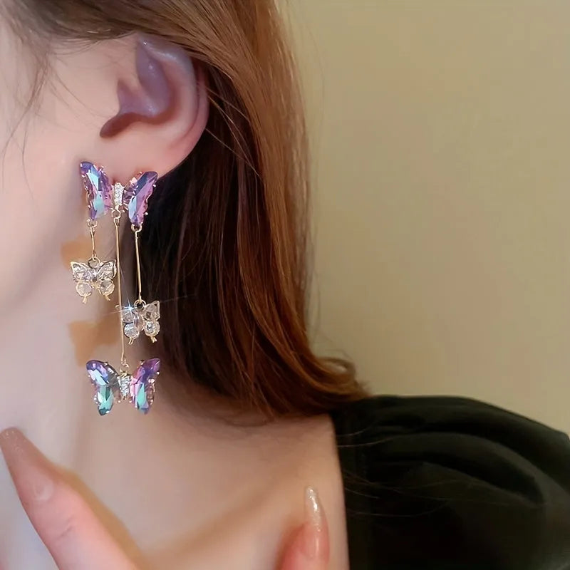 Close-up of women's silver needle blue purple butterfly alloy earrings with crystal flowers and a dangle tassel.