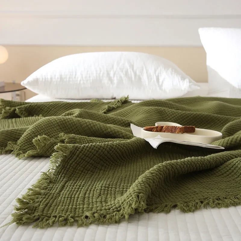 Four-layer gauze cotton blanket with tassel trim in navy blue colour laid flat