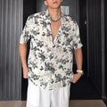 Loose black and white floral print short sleeve casual shirt on a hanger.