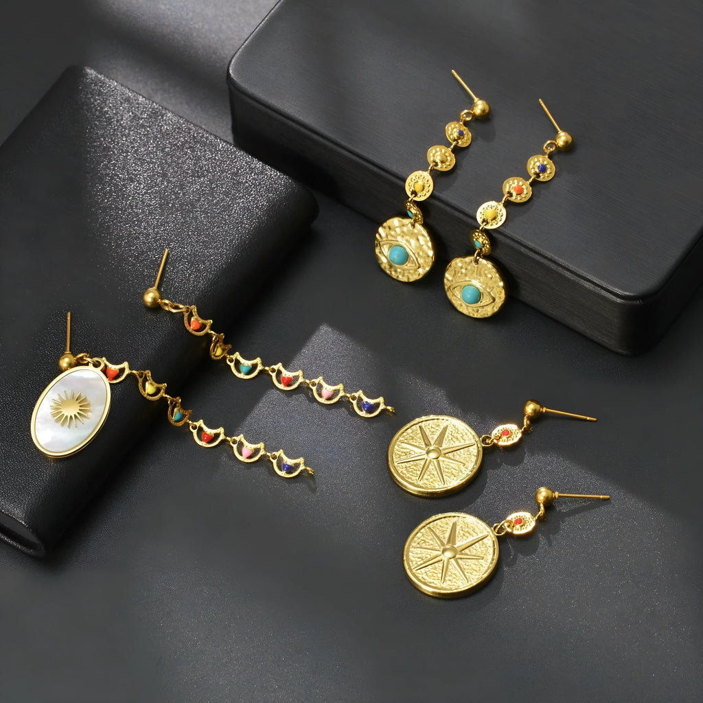 Three pairs of geometric stainless steel earrings on display: Eight Awn Star, Eye, and Shell Sun designs.