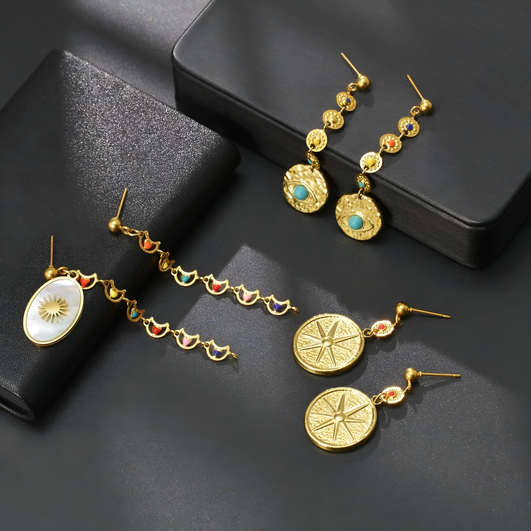 Three pairs of geometric stainless steel earrings on display: Eight Awn Star, Eye, and Shell Sun designs.