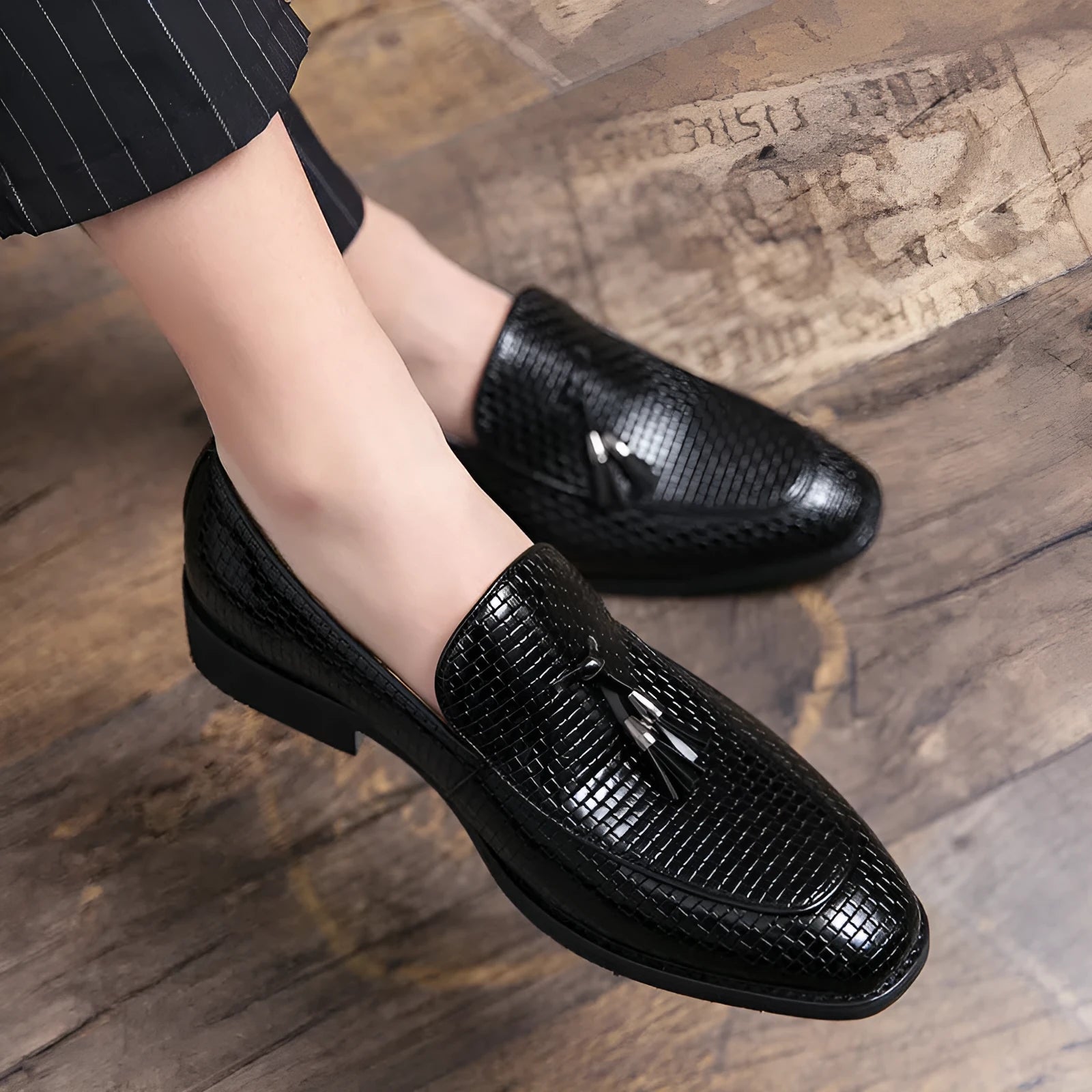 Men's black pointed toe slip on loafers with a tassel detail on the front.