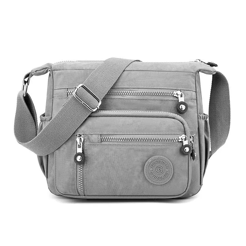 Soft nylon shoulder messenger bag in a square vertical shape with a single strap.