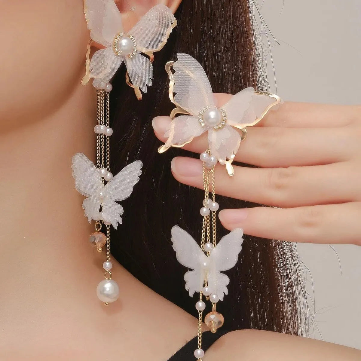 White butterfly earrings with lace pattern wings, pearl and rhinestone details, and dangling tassels
