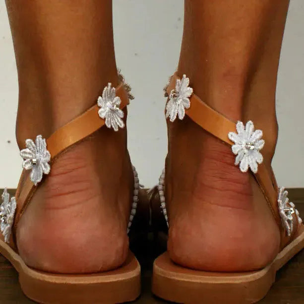 Brown women's sandals with flat rubber soles and decorative flower accents on the upper