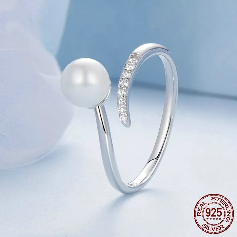 Sterling silver adjustable ring with a natural pearl on an open loop band.