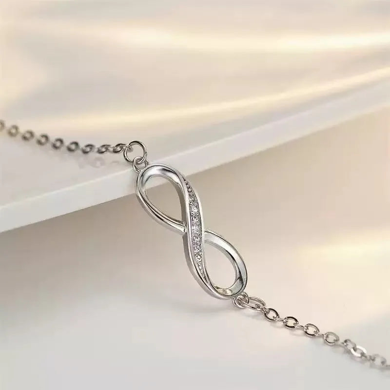 Silver copper Mobius strip diamond ring push-pull bracelet with lucky cat charm on display.
