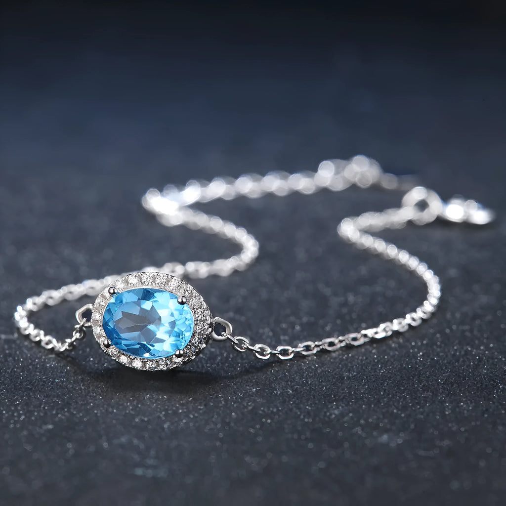 925 sterling silver jewellery set with blue topaz gems including geometric pendant necklace, earrings, ring, and bracelet.