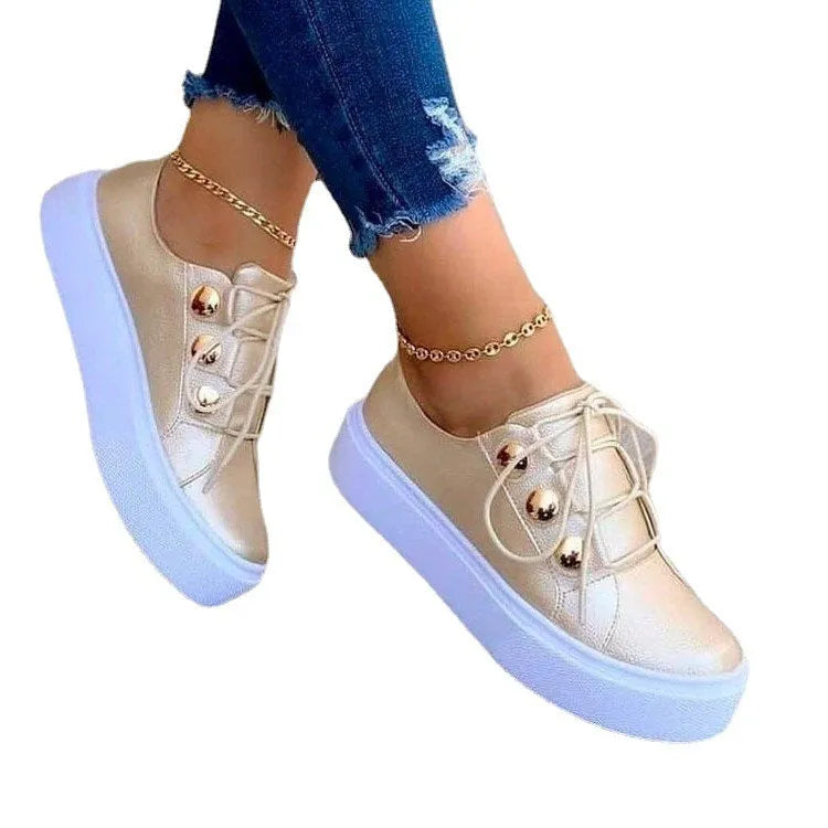 Women's white lace-up flats sneakers with rivet detail on the side and round toe.