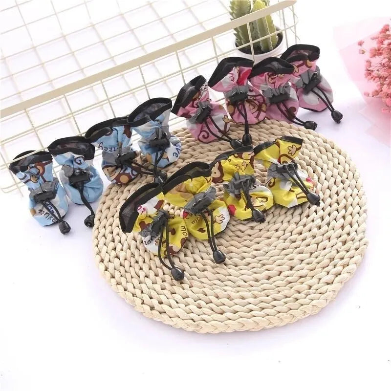 Multicolour set of four breathable cloth dog shoes with non-slip soft bottom on a white background