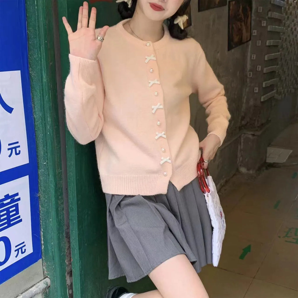 Women's solid colour cardigan with a bow and pearl buttons, in a light yellow acrylic knit.