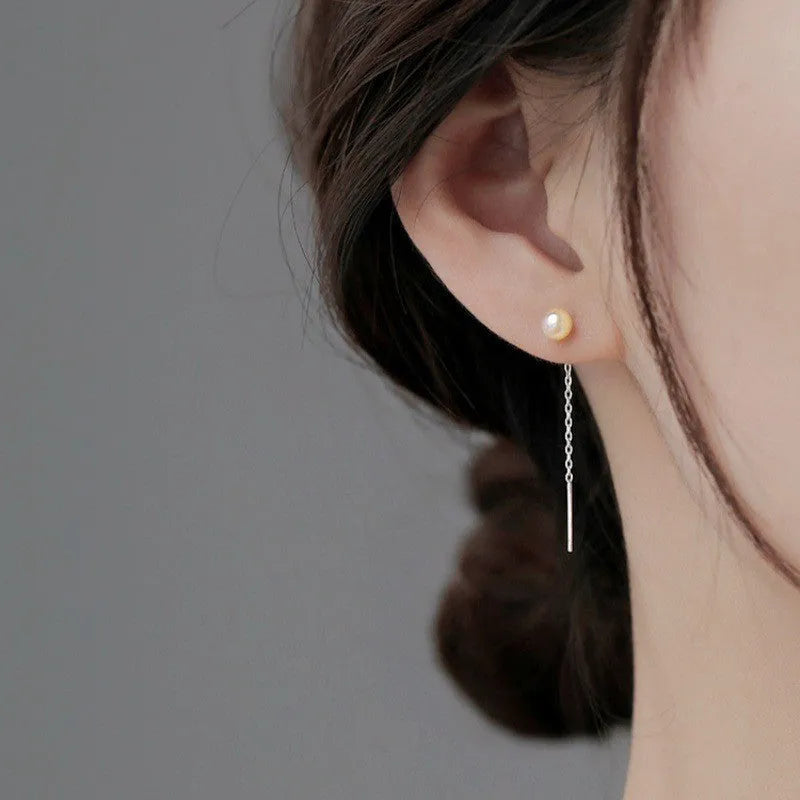 Sterling silver ear string with assorted small geometric and pearl charms on an alloy ear wire.
