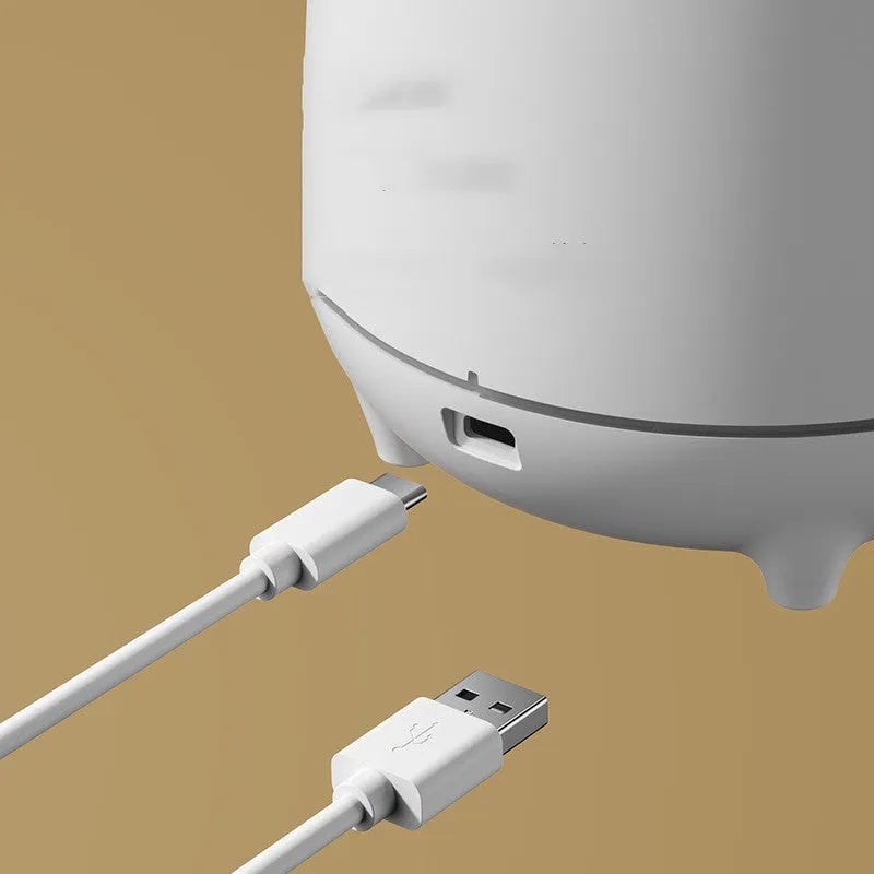 White volcano-shaped ultrasonic humidifier with USB cable on wooden surface