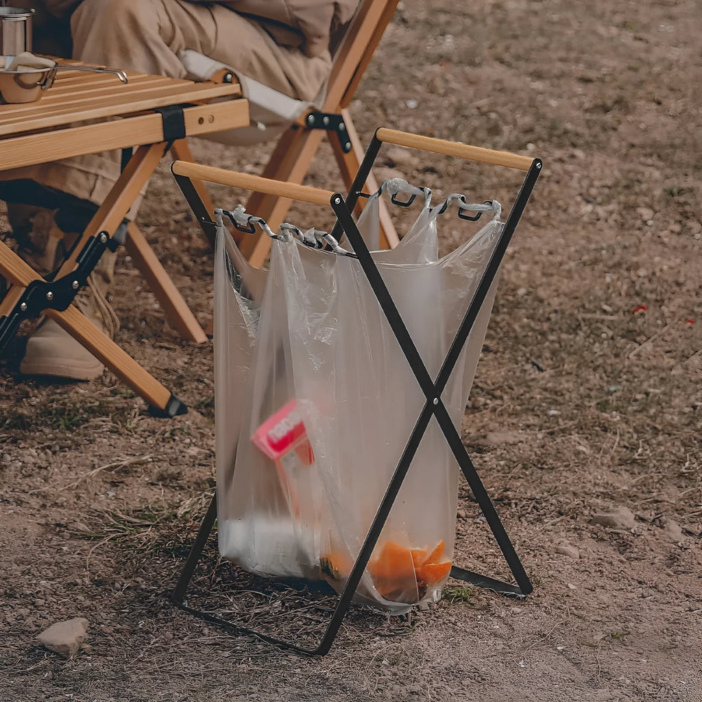 Black outdoor iron trash hanger with wooden handle in a folded position.