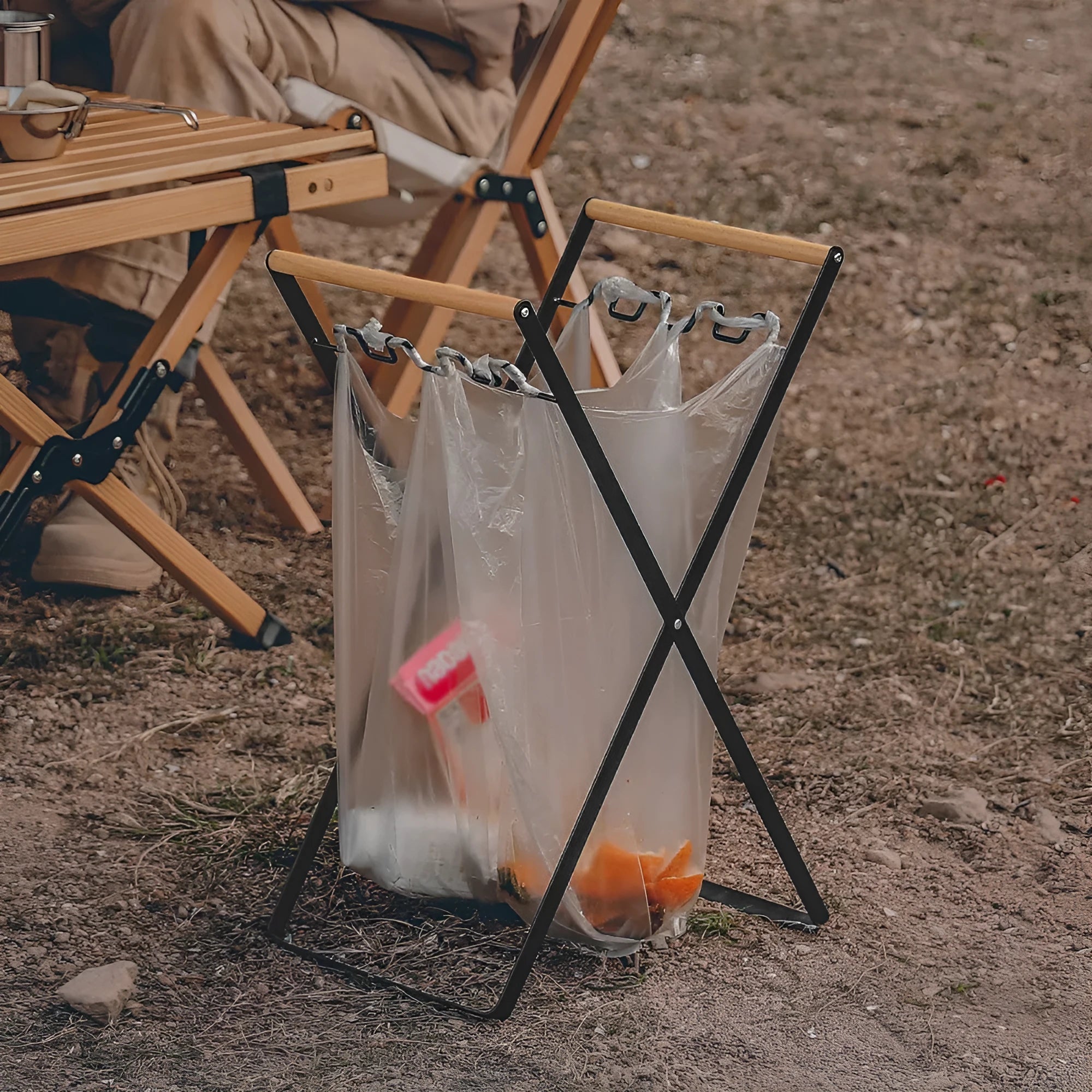 Black outdoor iron trash hanger with wooden handle in a folded position.
