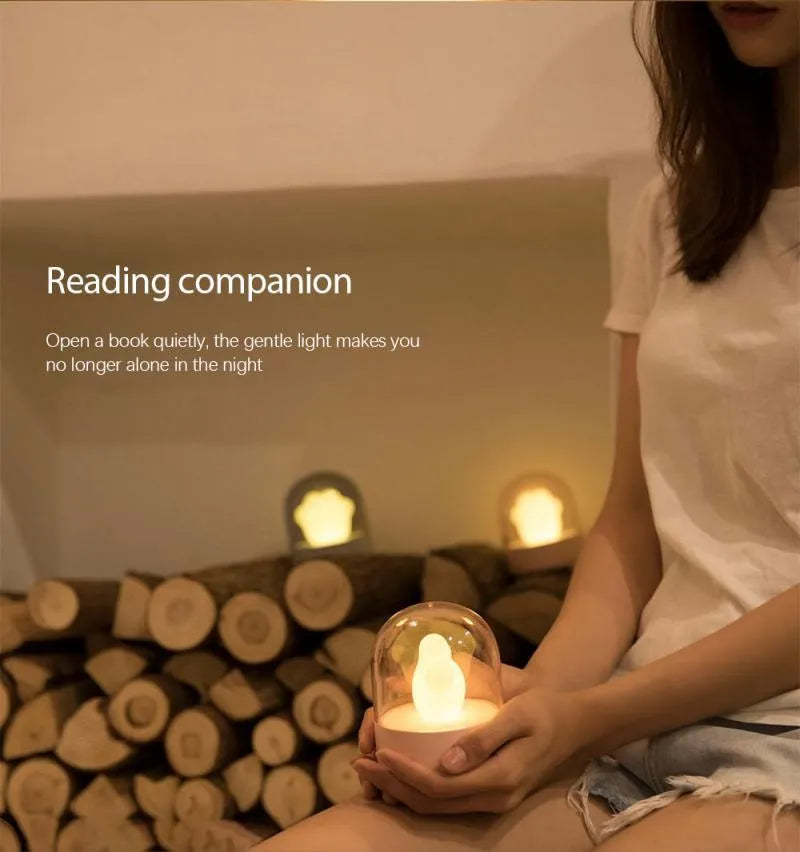 Grey cat paw shaped musical night light with USB charging cable on wooden desktop