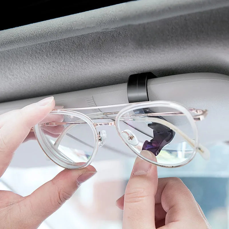 Black plastic multifunctional clip for car sun visors, designed to hold sunglasses and cards.