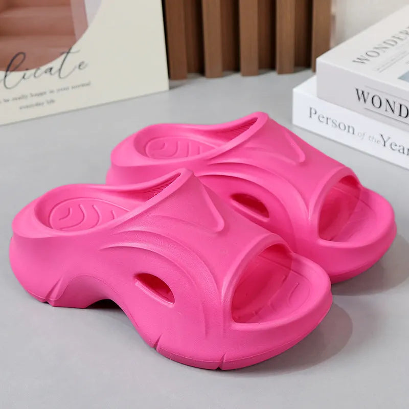 Women's white thick-soled EVA slippers with round toe on a sandy beach.