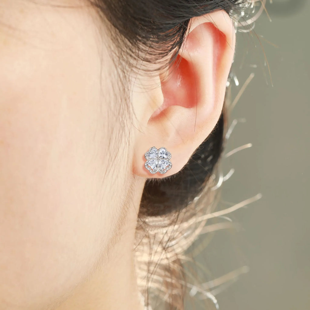 Close-up of women's 925 silver drop earrings with a four-leaf clover charm and heart zircon, in white gold colour.