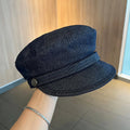 Adjustable octagonal denim newsboy hat in dark blue with contrast brim on white background
