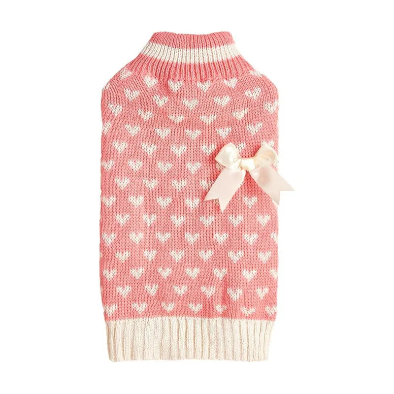 Small dog wearing a red knitted jumper with a white love heart motif on the chest.