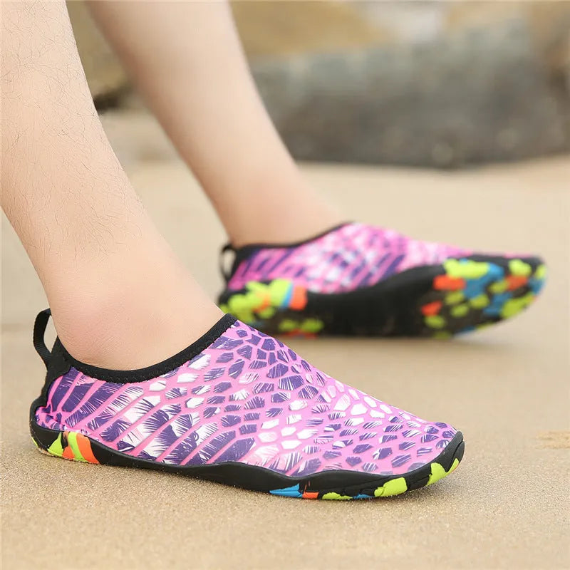 Blue and camouflage coloured beach wading shoes with Lycra uppers on a sandy background