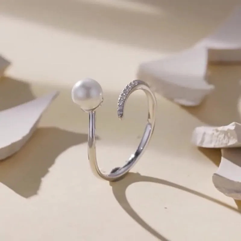 Sterling silver adjustable ring with a natural pearl on an open loop band.