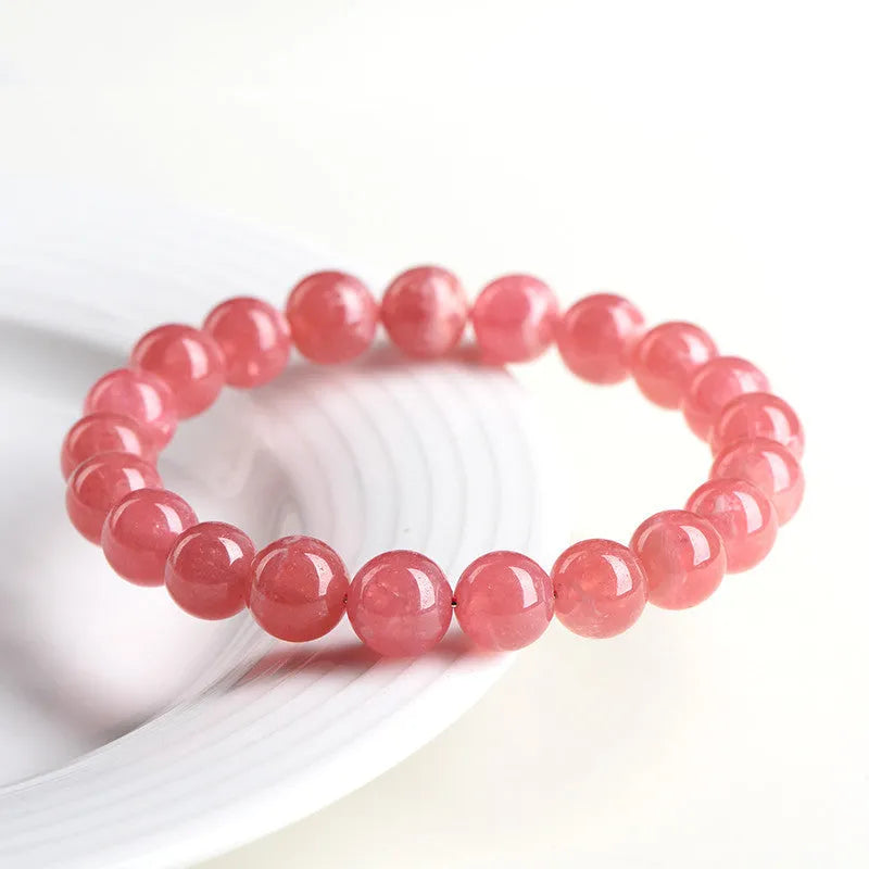 Women's geometric red rhodochrosite crystal bracelet with a longevity lock clasp on a wrist.