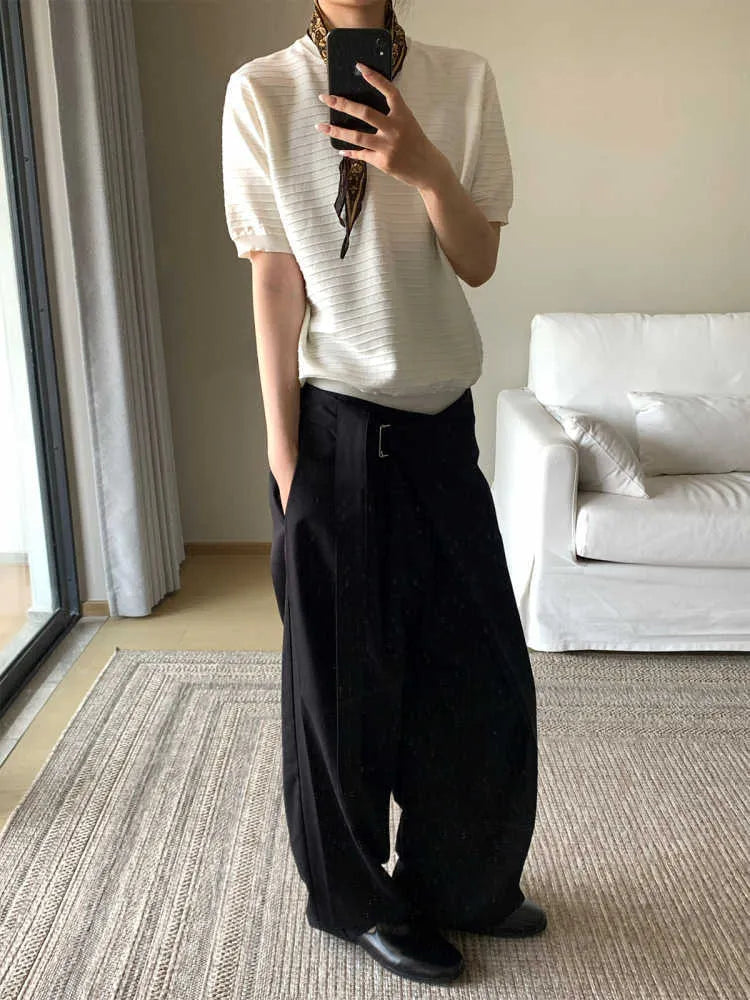 Black straight-leg trousers with single pleat front and adjustable waistband on hanger