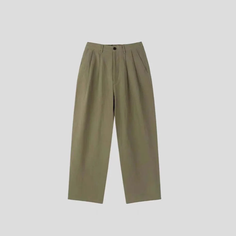 Men's lightweight apricot coloured loose-fit linen trousers laid flat, showing zip fly and relaxed leg style.