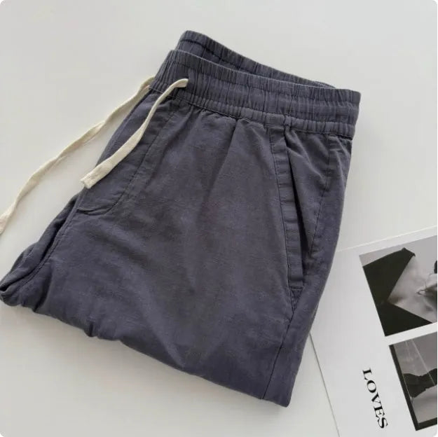 Man wearing beige loose straight casual trousers with a drawstring waistband.