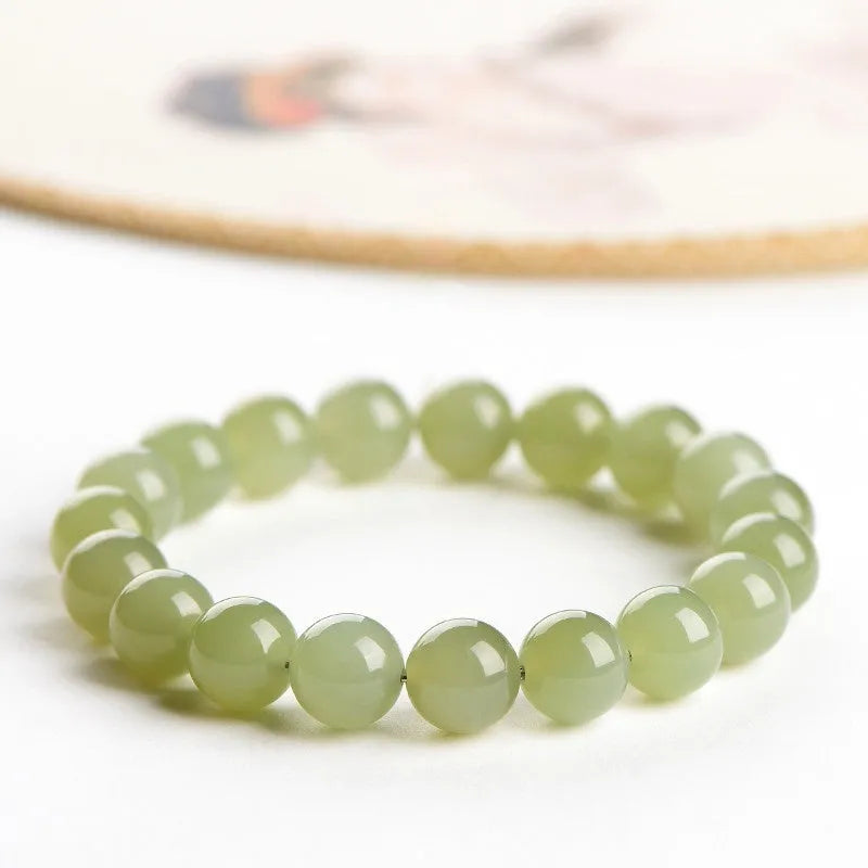 Polished Hetian jade ball bracelet with ice-like translucent beads in spherical shapes on a plain background