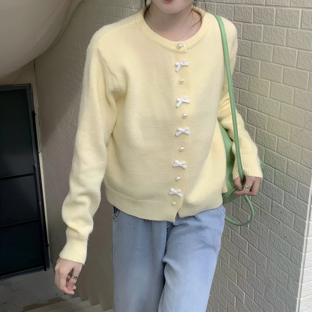 Women's solid colour cardigan with a bow and pearl buttons, in a light yellow acrylic knit.