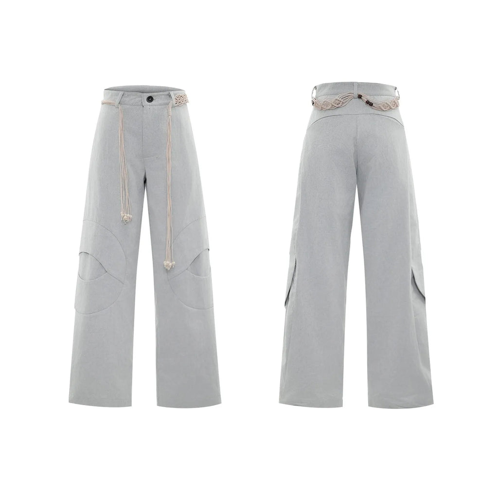 Men's dark blue loose fit straight-leg trousers showing 3D cutting, belt stitching, and tassel details on pockets and zipper.