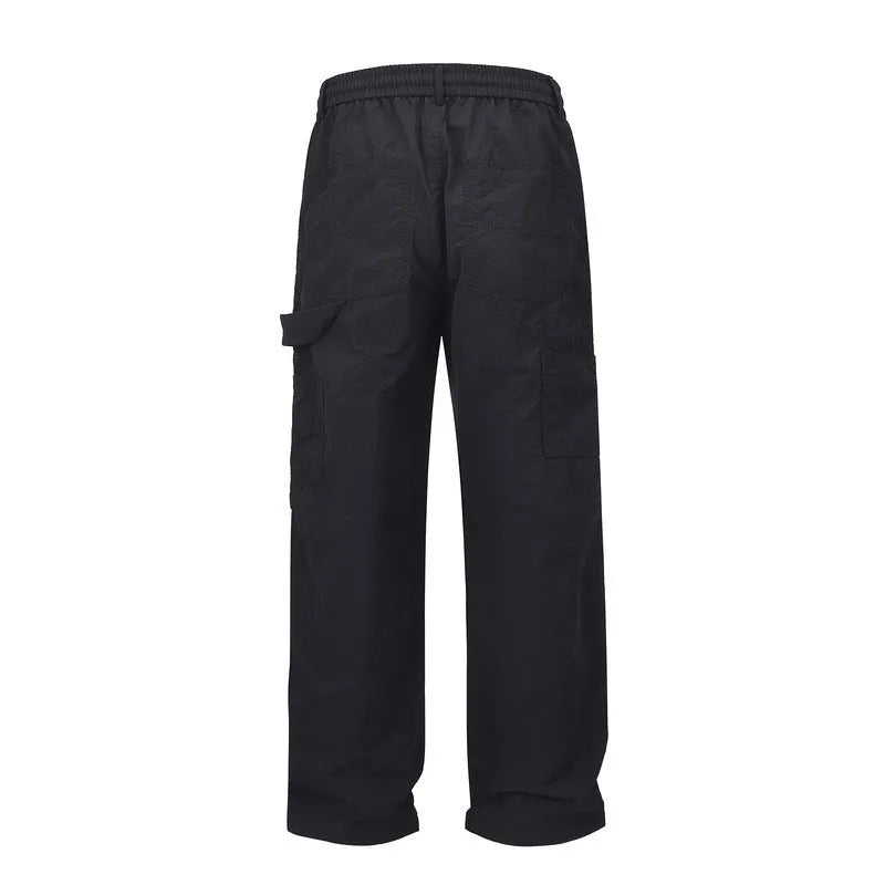 Men's baggy paratrooper pants in black with elastic waist and drawstring, side view on model